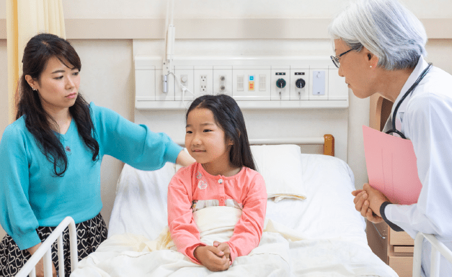 Young girl in hospital bed with mother and doctor